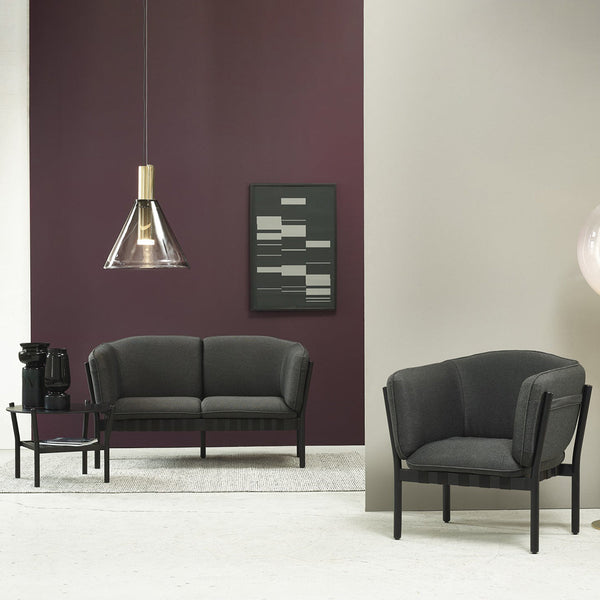 Stylish dark gray armchair and sofa against a deep burgundy wall, complemented by geometric patterns in decor.