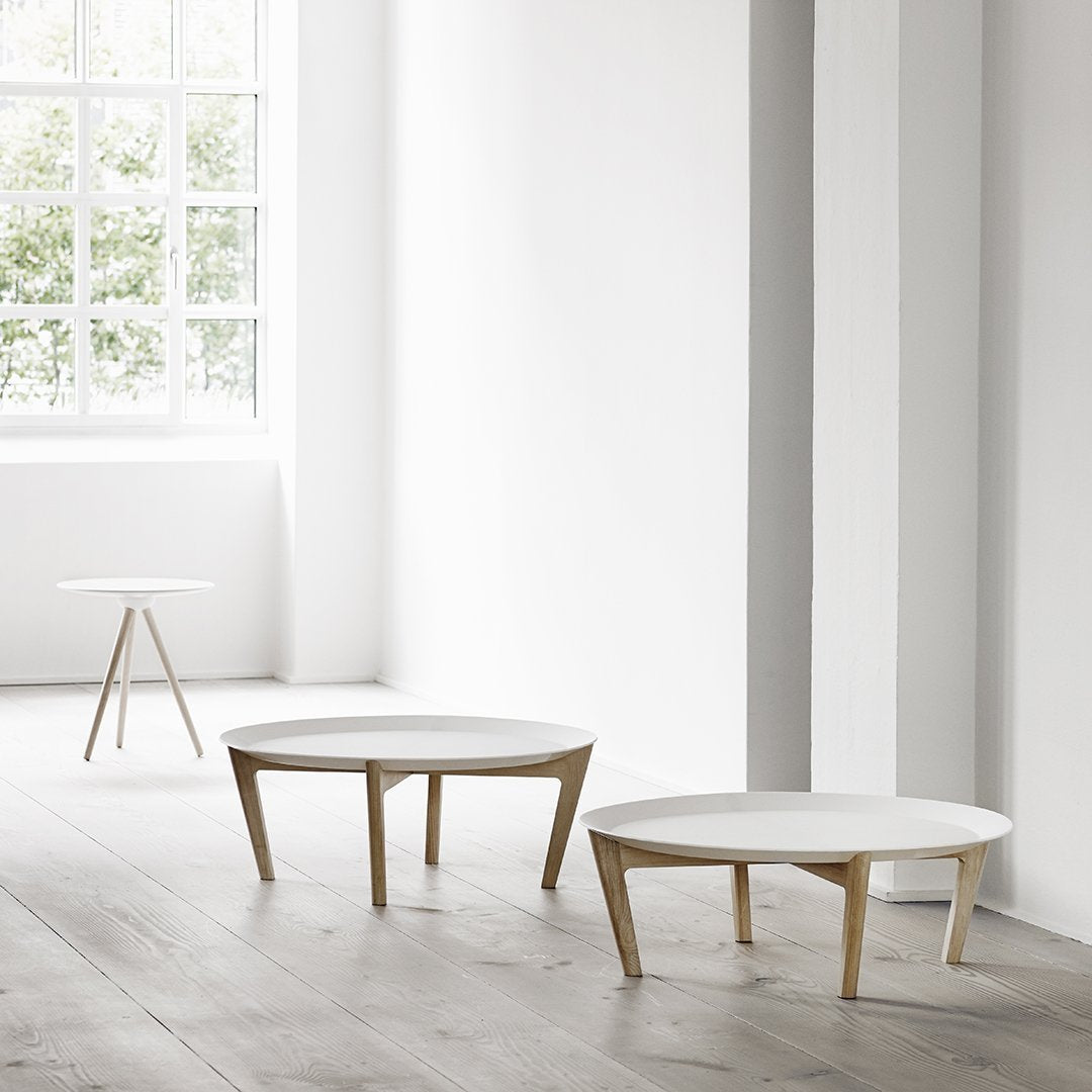 White round coffee tables with natural wood legs in a minimalistic, bright room.