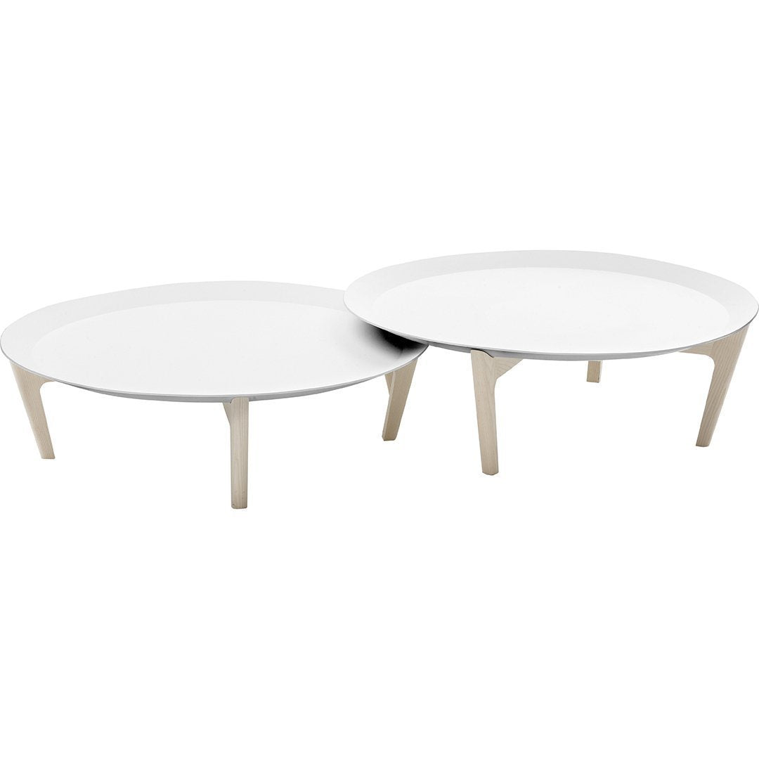 "Set of two minimalist round coffee tables in smooth white finish with sleek beige legs."