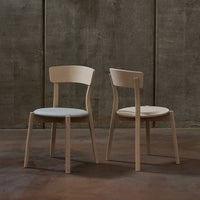 Light wood chairs with smooth, minimalist design; soft gray cushions highlight a modern aesthetic.