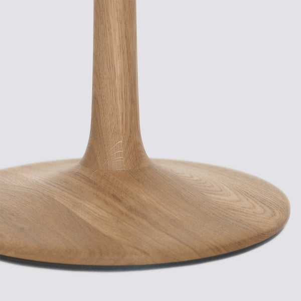 Natural wood grain table base with a smooth, circular design in light oak color. Elegant and modern aesthetic.