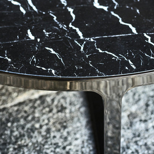 Black marble table top with striking white veining and a textured silver base. Elegant and modern design.
