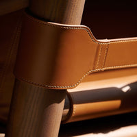Tan leather strap with contrasting stitching, attached to a wooden frame, showcasing a smooth, clean finish.