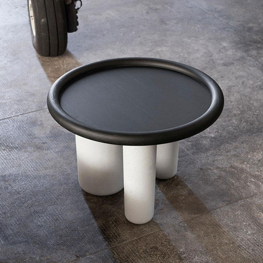Black round tabletop with a smooth finish and four white cylindrical legs in a modern minimalist design.