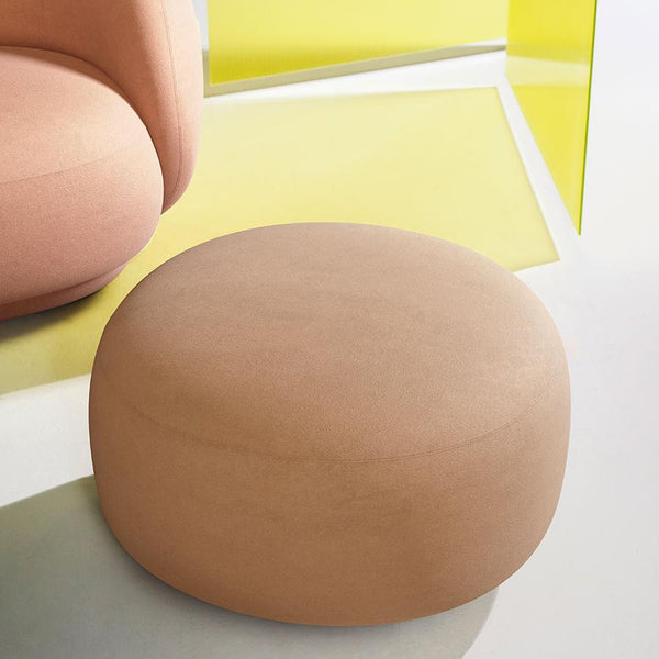 Round beige pouf on a modern surface with vibrant yellow geometric accents, featuring a soft, smooth texture.