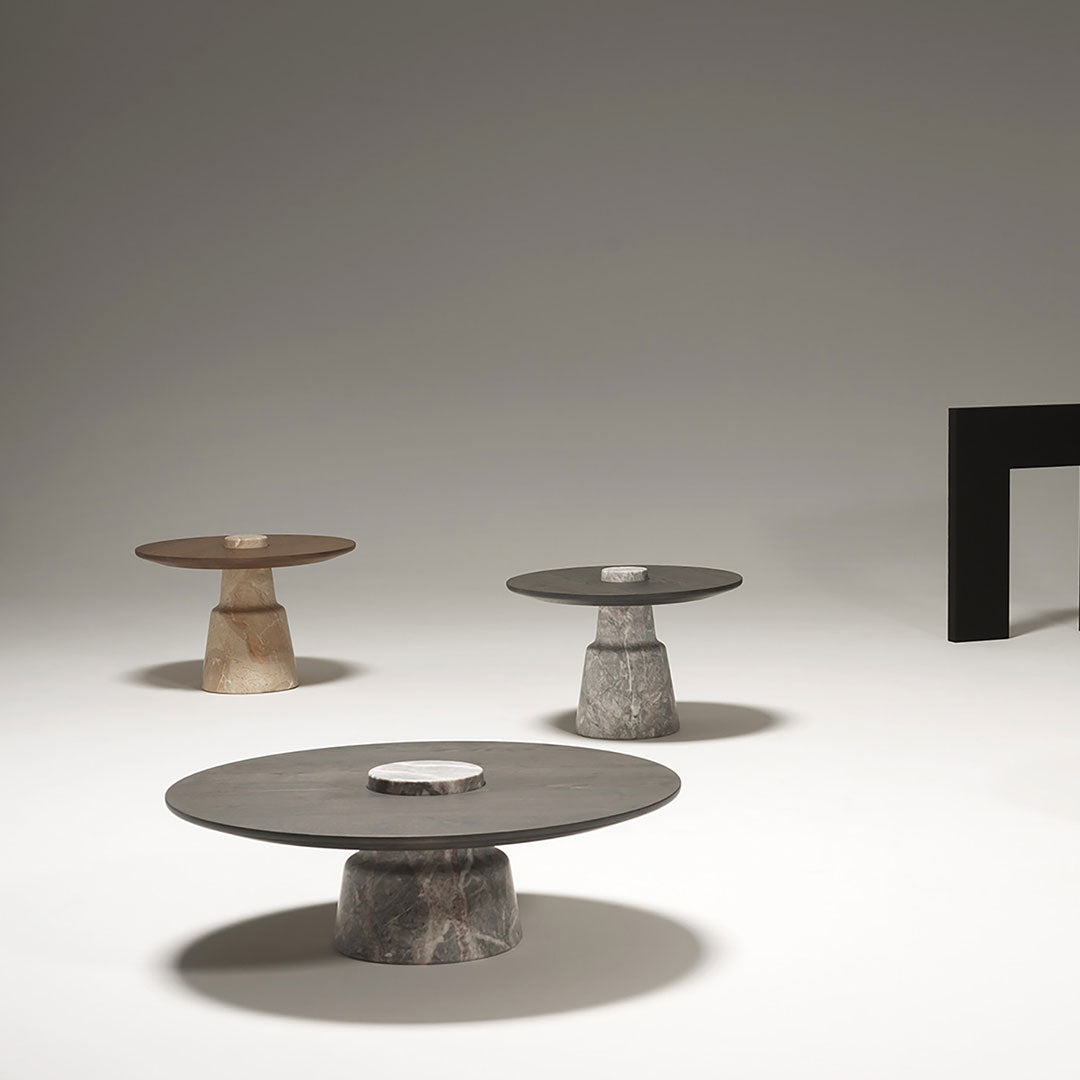 Three modern coffee tables in grey, beige, and brown hues, featuring circular tops and textured bases.
