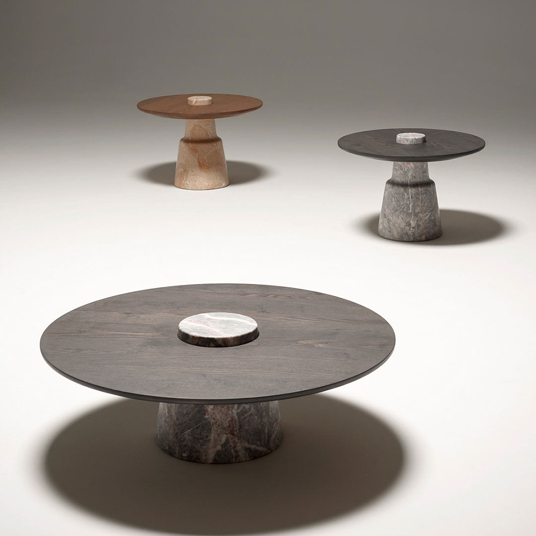 Three modern coffee tables featuring brown, gray, and black colors with circular tops and unique stone bases.