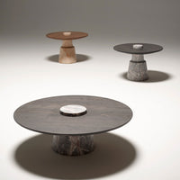 Three modern coffee tables featuring brown, gray, and black colors with circular tops and unique stone bases.
