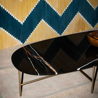 Sleek black marble coffee table with white and gold veining, set against a yellow and teal zigzag patterned wall.