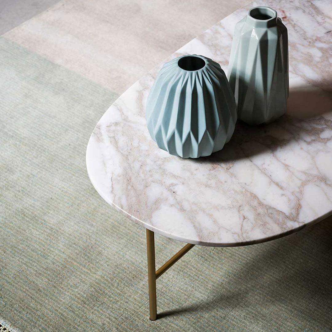 Light green vases on a marble tabletop, with soft pastel patterns in the background. Elegant modern decor.