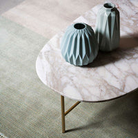 Light green vases on a marble tabletop, with soft pastel patterns in the background. Elegant modern decor.