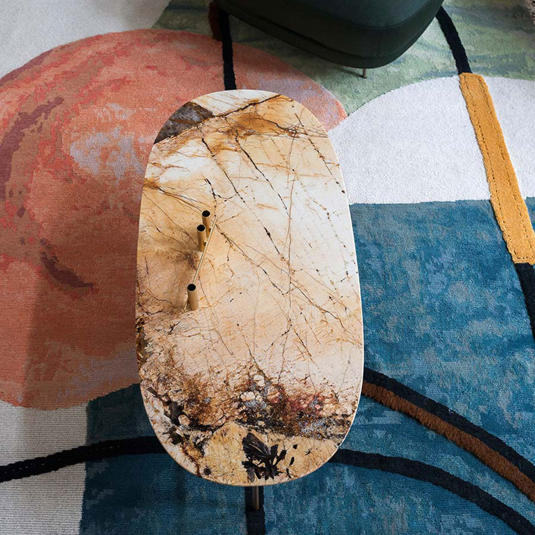 Marble tabletop, cream and brown tones with striking veins, set on a colorful patterned rug featuring blue and red circles.