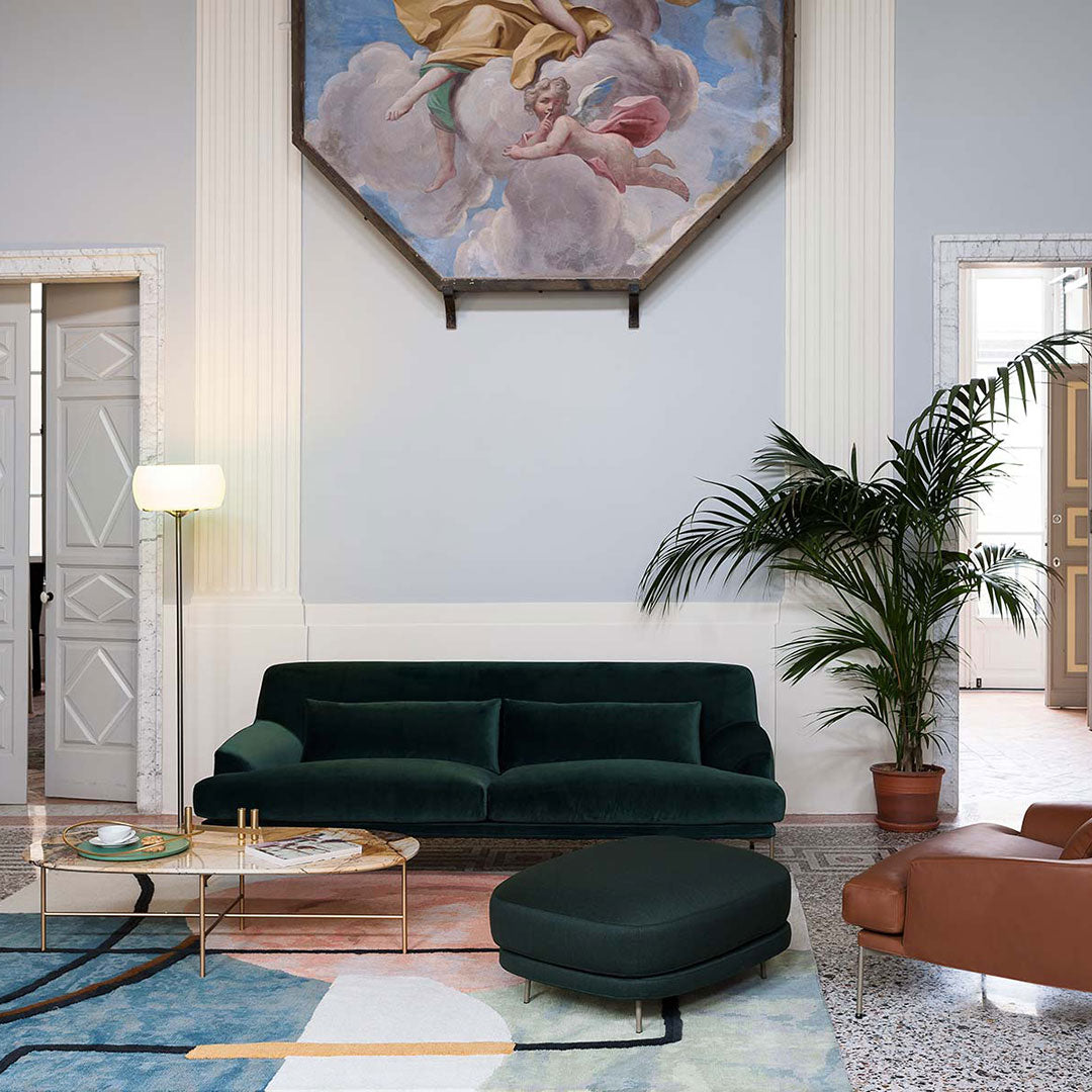 "Elegant dark green velvet sofa with modern patterns, complemented by gold accents and a neutral-toned rug."