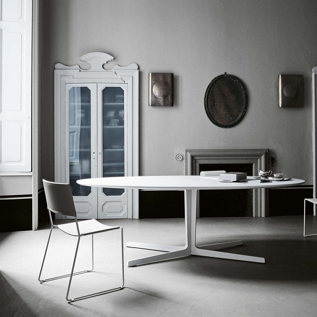 Stylish white oval dining table with a sleek gray chair, set in an elegant monochrome interior.