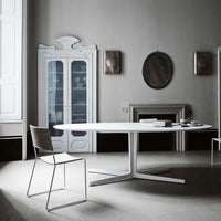 Stylish white oval dining table with a sleek gray chair, set in an elegant monochrome interior.