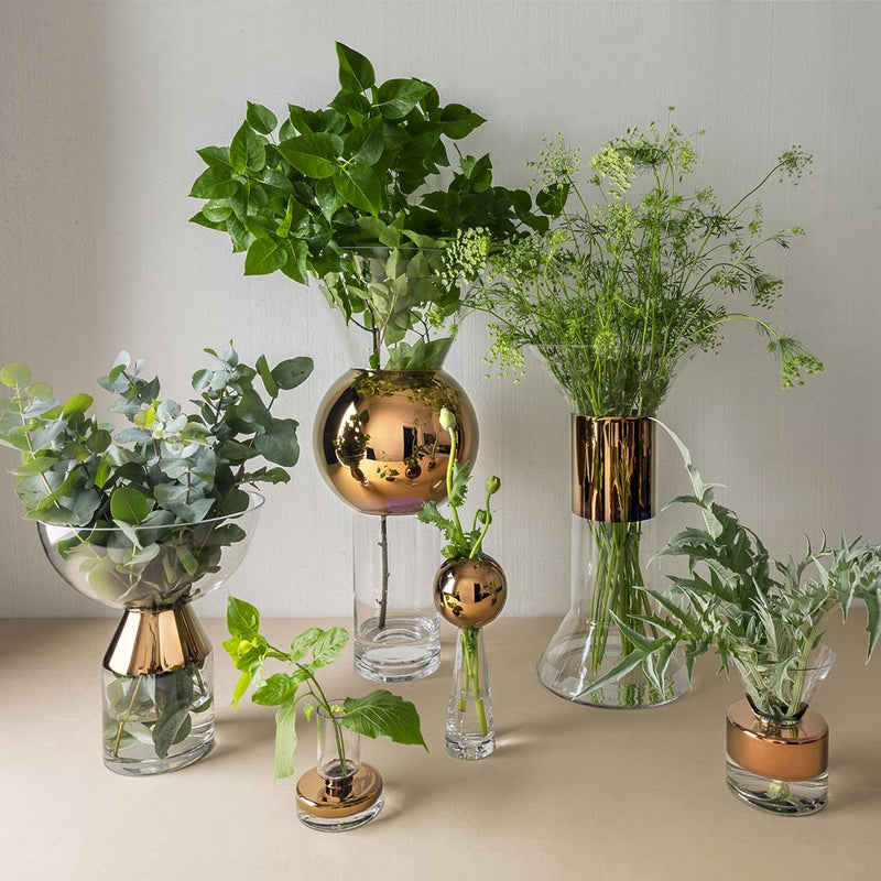 "Assorted glass vases featuring green foliage with gold and copper accents, showcasing elegant textures and patterns."