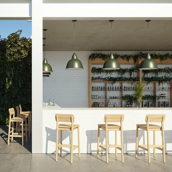 "Modern bar featuring green pendant lights, wooden stools, and lush greenery against a white and wood backdrop."