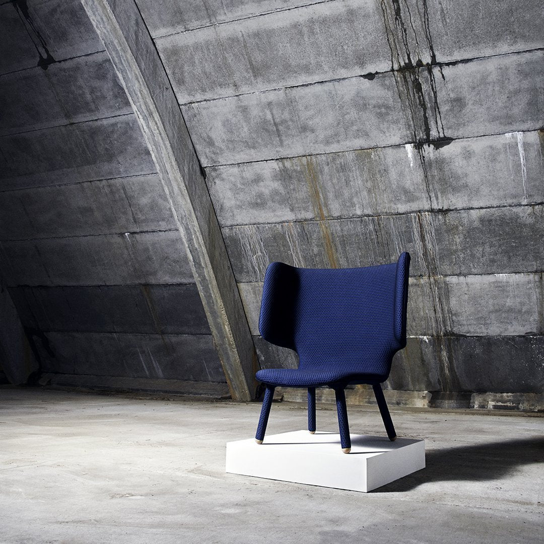 Navy blue chair with a modern, minimalist design and smooth, solid fabric texture against a concrete backdrop.