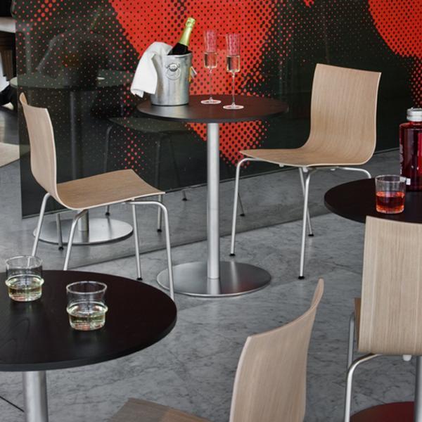 Modern black and silver tables with light wood chairs, set against a vibrant red and black patterned backdrop.
