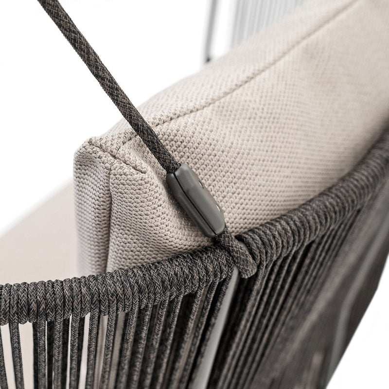 Gray woven chair with a soft beige cushion, featuring sleek black accents and a unique linear pattern.