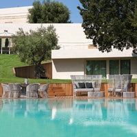 "Elegant gray outdoor furniture with a sleek pattern, set against a turquoise pool and lush greenery."