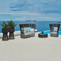 Black wicker outdoor seating with light gray cushions and aqua accents, set against a blue ocean backdrop.