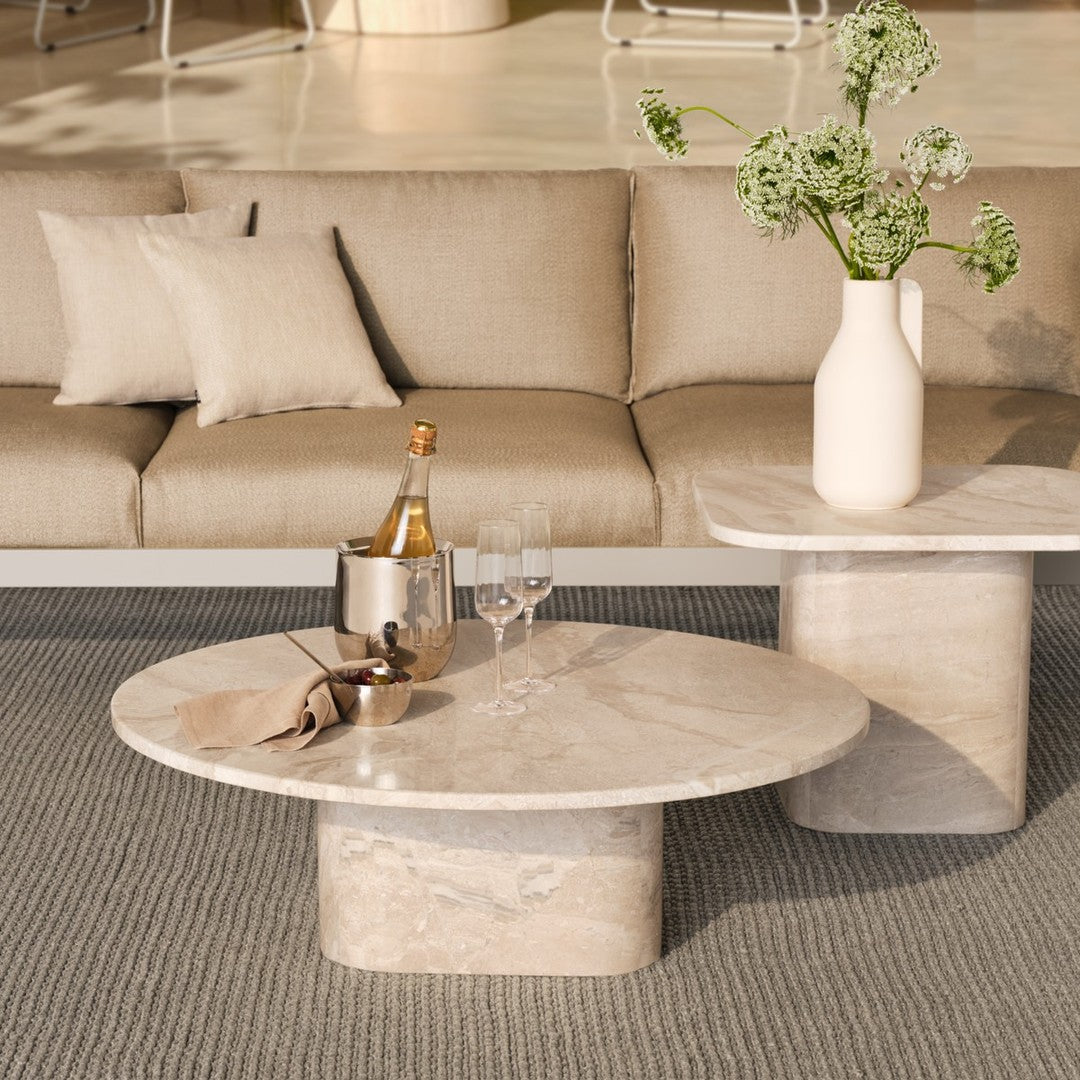 "Elegant round marble coffee table with soft beige hues and subtle veining, paired with neutral-toned decor."
