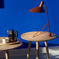 Stylish brown lamp on wood table against a vibrant blue wall, featuring minimalist design and modern color contrast.