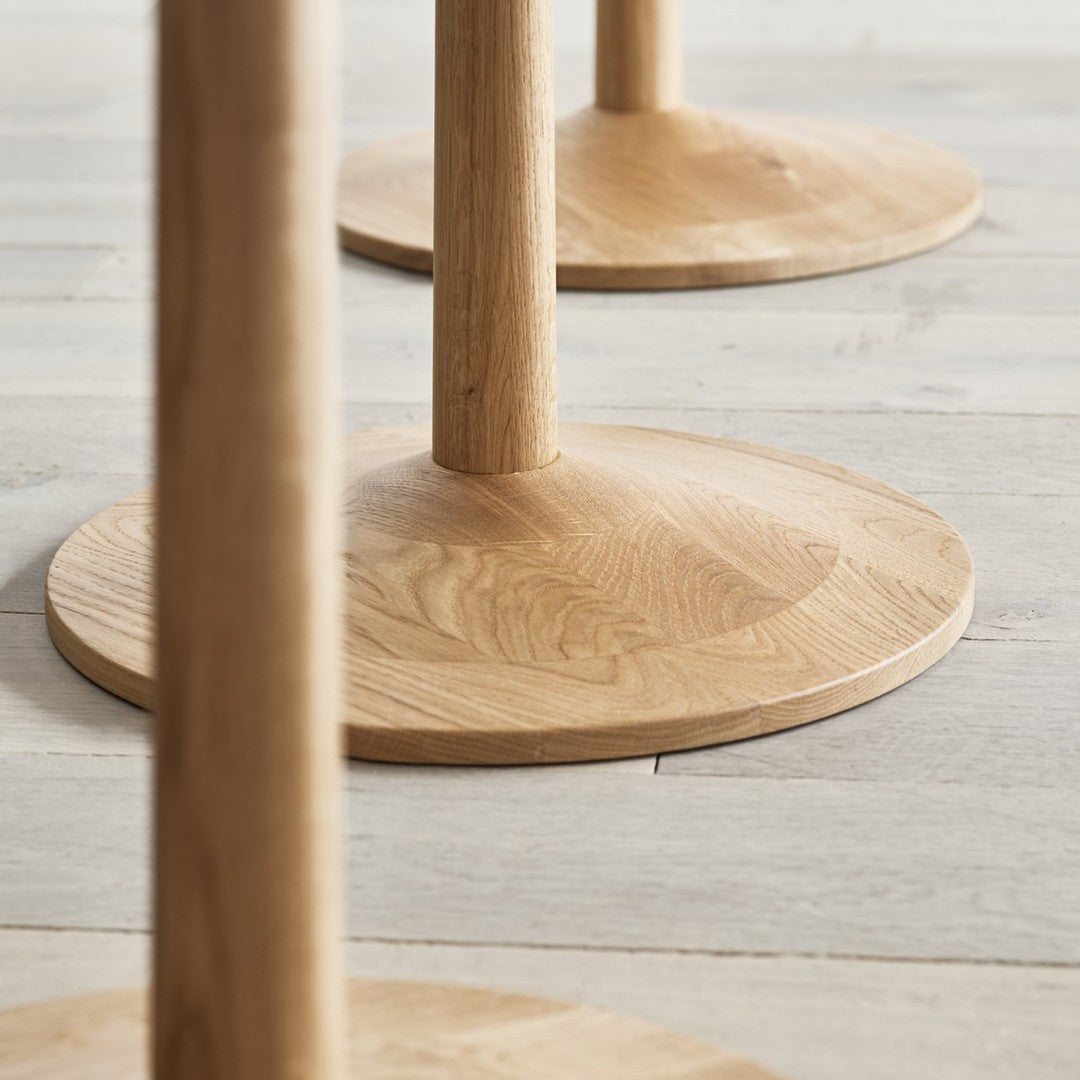 Natural wood table bases with smooth, light oak finish and subtle grain patterns on round surfaces.