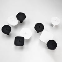 Black and white geometric knobs in varied shapes, arranged in a modern pattern on a light background.