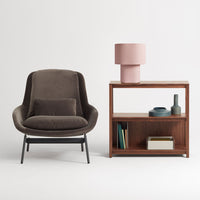 "Brown velvet armchair, pink lamp, and wooden bookshelf with clean lines and minimalist design."