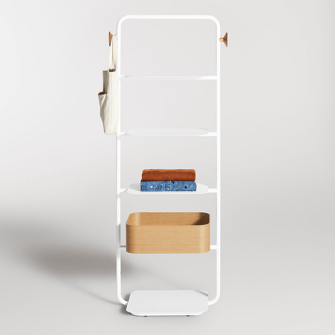 White metal shelving unit with layered shelves, featuring brown and blue towels, and a beige storage basket.