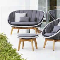 Gray cushioned outdoor seating set with curved patterns and light wood legs, featuring matching pillows.