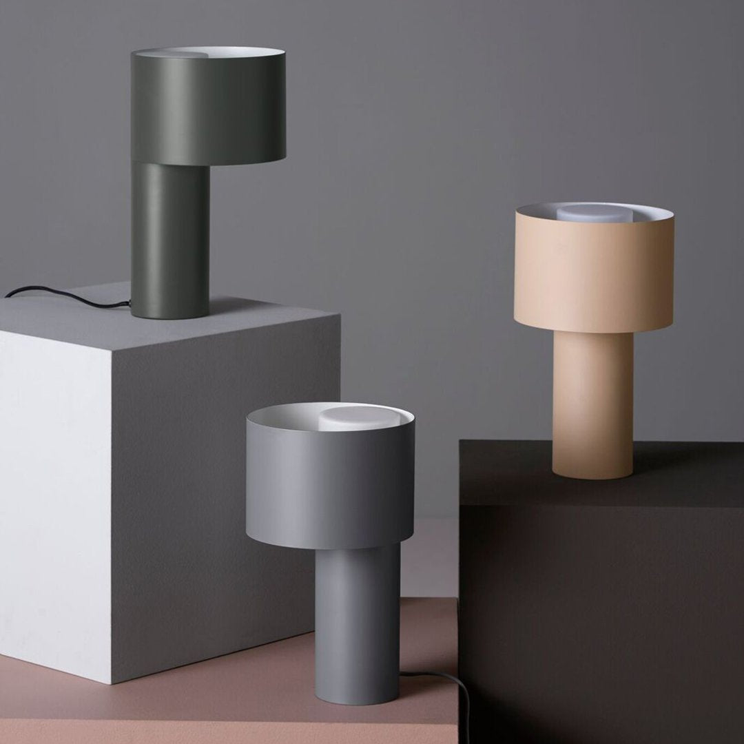 Modern table lamps in green, gray, and beige with sleek, minimalist designs on geometric pedestals.
