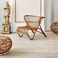 Natural rattan chair with a woven pattern, featuring warm brown tones, paired with round wicker side tables.