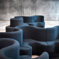 Curved, modular seating in deep navy blue fabric against a textured gray concrete background. Stylish and modern design.