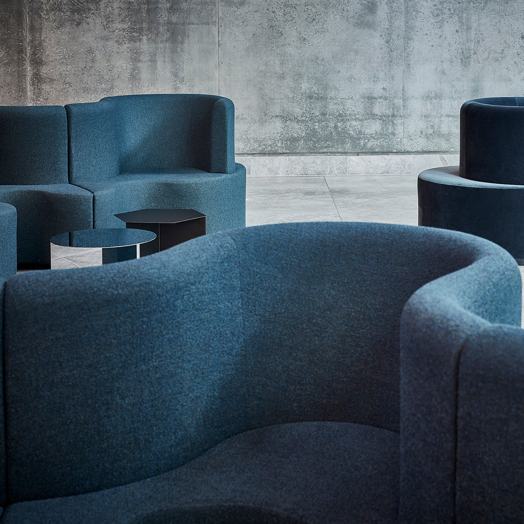 Dark blue upholstered chairs with soft textures against a concrete backdrop. Simple geometric shapes and patterns.