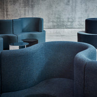 Dark blue upholstered chairs with soft textures against a concrete backdrop. Simple geometric shapes and patterns.