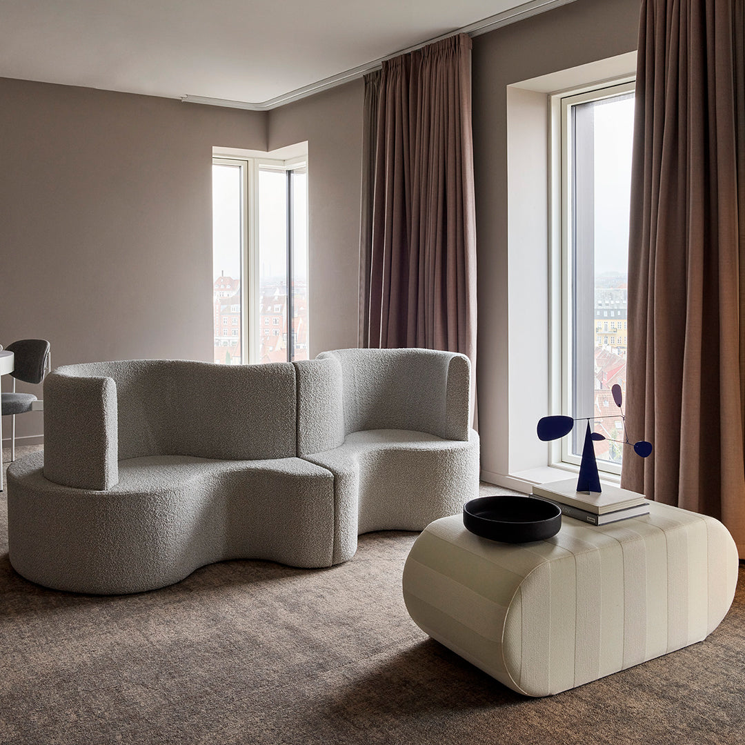 Modern light gray textured sofa with curved lines and a soft cream striped coffee table, featuring elegant neutral tones.