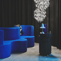 Vibrant blue textured seating with black accents and a clear chandelier against a dark backdrop.