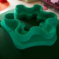 Curvy green modular seating on a dark green carpet, featuring a bold, playful design.