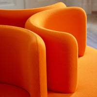 Bright orange armchair with soft, curved upholstery, showcasing a modern design and vibrant color.