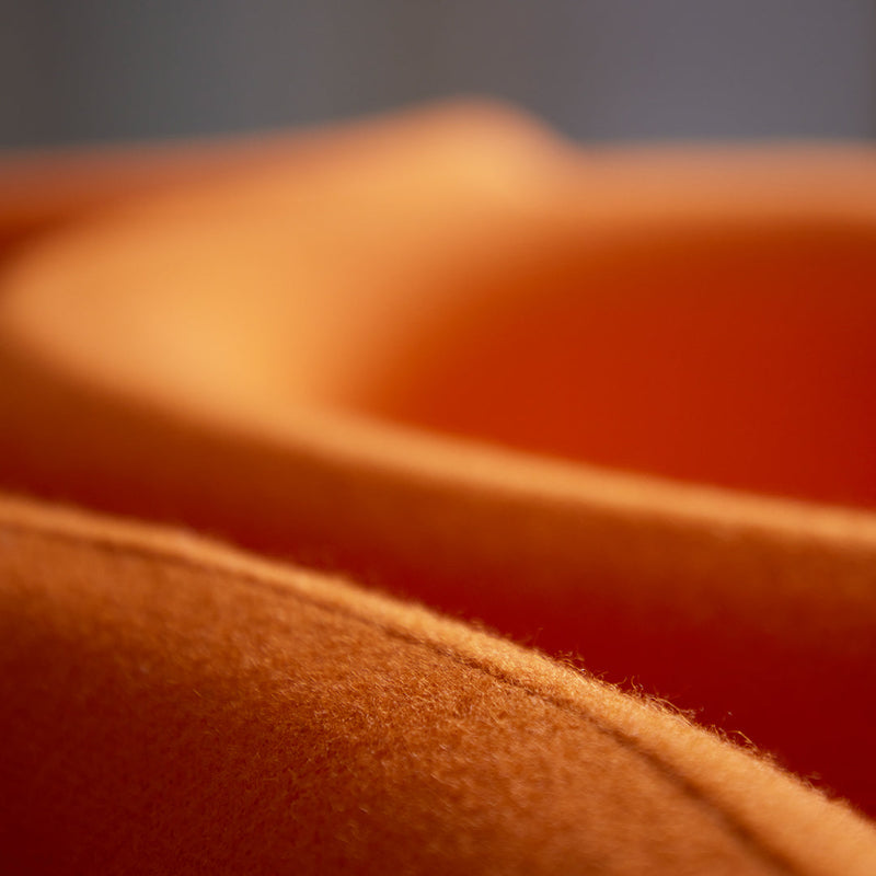 Close-up of soft, textured fabric in shades of warm orange, showcasing smooth curves and a cozy feel.