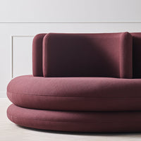 Burgundy upholstered sofa with smooth, rounded shapes and a minimalist design. Modern and stylish home decor accent.