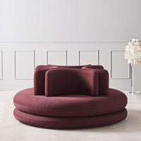 Burgundy circular sofa with minimalist design and smooth texture, featuring layered cushions and modern aesthetic.