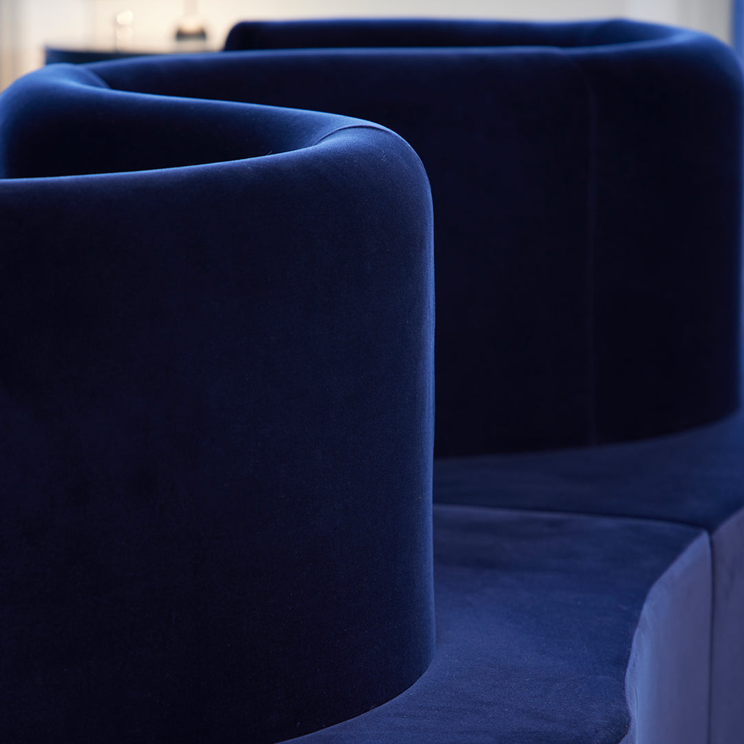 Dark navy blue velvet sofa with smooth curves and a modern design, showcasing luxurious texture and rich color.