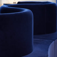 Dark navy blue velvet sofa with smooth curves and a modern design, showcasing luxurious texture and rich color.