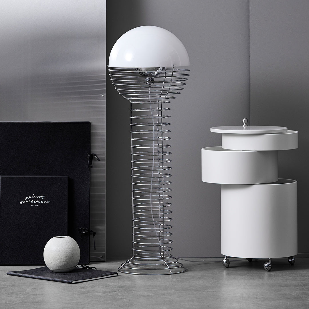 White globe floor lamp with wire base, surrounded by sleek white furniture and dark accents, creating a modern monochrome aesthetic.