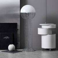 White globe floor lamp with wire base, surrounded by sleek white furniture and dark accents, creating a modern monochrome aesthetic.