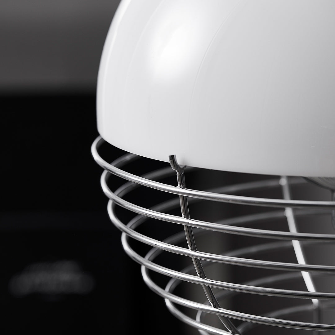 Close-up of a sleek white mixer head with a shiny silver wire guard, against a dark background.